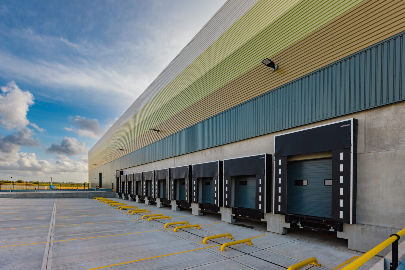 Exterior view of a large industrial warehouse with a row of loading by doors